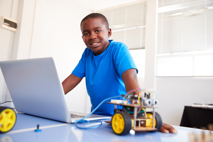 Image of an 11 Year Old Boy with a Robot toy and computer