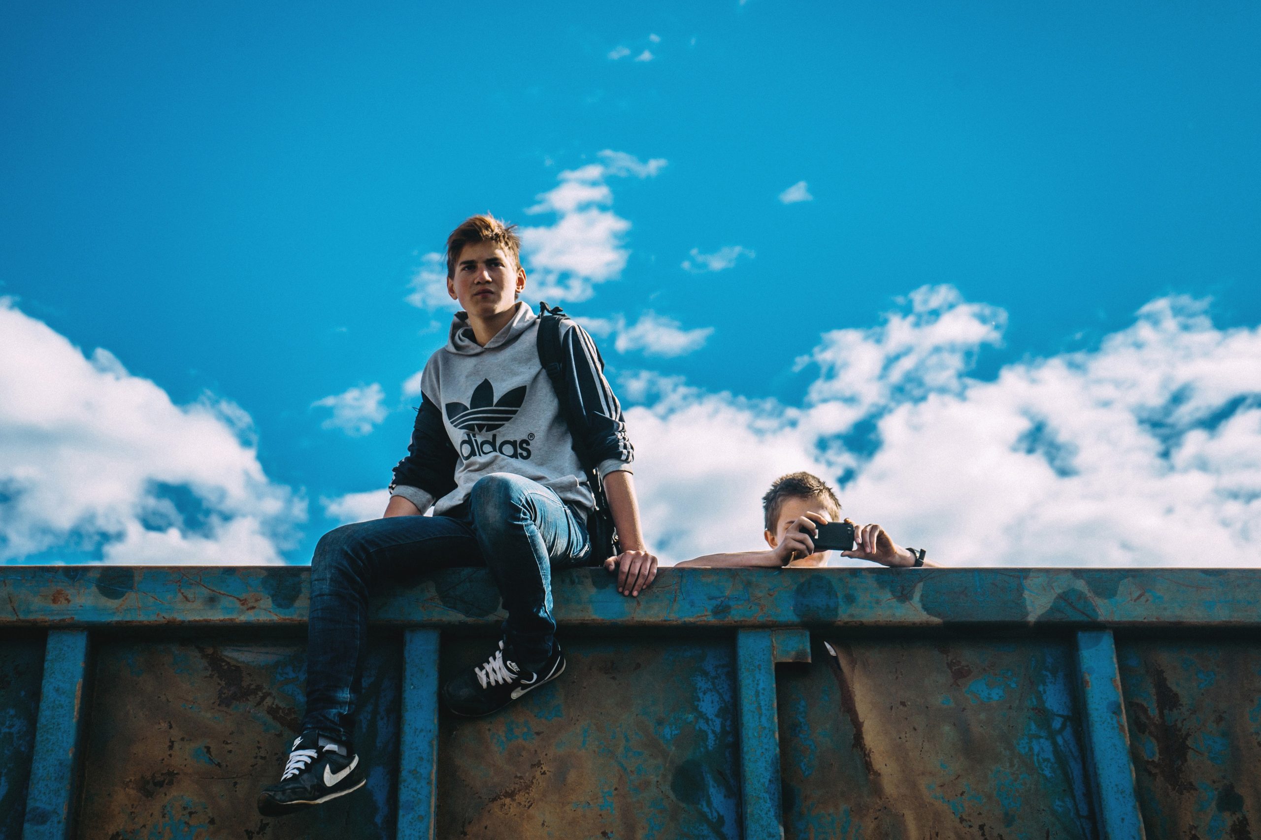 image of two 18 year old guys outside climbing over a dumpster