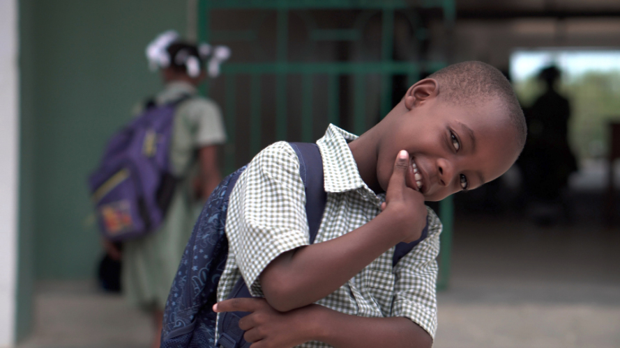 Image of a 6 Year Old African American Boy Smiling with his backpack on at school