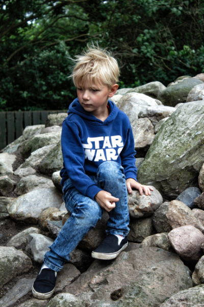 Image of a 7 Year Old Boy Sitting on some rocks at a Park