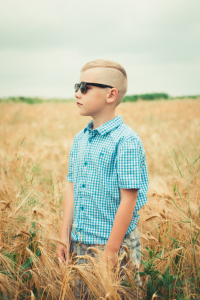 Image of an 8 Year Old Boy Wearing Sunglasses while standing in a wheat field